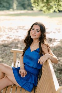 Brunette girl wearing a royal blue dress with her hands on her hips
