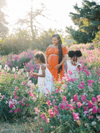 Mom looking over her two daughters as they smell sweet peas in Discovery Park