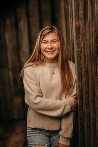 A senior student from Germnatown High School leans against a wooden beam in our Waukesha studio.