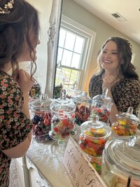 Bride smiling at a decorated mirror and candy station inside The Love Loft