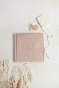 Pink velvet displayed with baby bow and bonnett