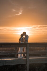 Couple kissing at sunset on a wooden deck during a romantic New England wedding portrait.