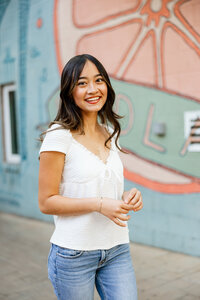 High school senior girl posing in an urban alleyway with brick walls and street art, senior photography by Kaitlyn Dawn Photography.