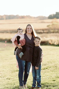 Mother holding her two children in a golden autumn field during a Cleveland family photography session