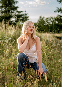 Oregon City high school senior girl squatting in a field of wildflowers at Powell Butte Nature Park for her Senior Portraits.