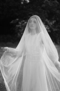Poetic and cinematic portrait of a bride underneath a sheer veil, emphasizing soft light and emotional storytelling.