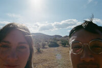 Bride and groom peeking into the camera in the desert.