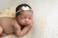 Newborn baby posed with on a soft yellow backdrop during her studio session at Jennifer Brandes Photography in New Ulm, Minnesota.