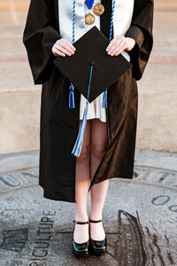 Detail photo of graduation attire and senior standing on the MTSU seal