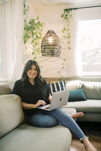 Online interior decorator, Michelle, sitting on couch with laptop