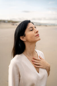 Zen uitstralende branding foto van vrouw op het strand met hand op haar hart