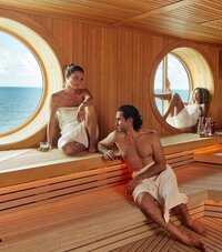Couple enjoying ocean views by a porthole on a Virgin Voyages cruise, highlighting luxury travel.