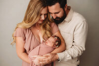 New Parents pose with their infant for Newborn Pictures at Holy City Babies Portrait Studio in Charleston, SC.