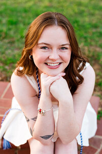 Headshot photo of senior girl smiling with hands under her chin