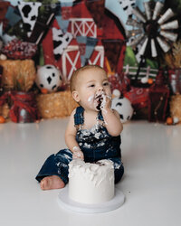 Joyful first birthday moment as baby boy claps frosting-covered hands during his barnyard cake smash.
Photograph by Yucaipa cake smash photographer Kaitlyn Dawn Photography.