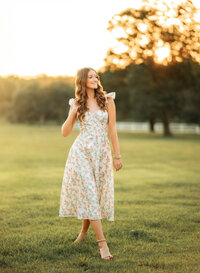 Senior portrait in downtown Magnolia Springs, Alabama — playing with her hair in a lush green field.