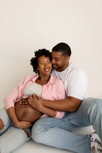 candid moment of expecting couple holding each other tenderly in studio portrait for maternity photoshoot