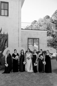 black and white image of bride with bridesmaids holding parasols