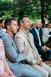 Male couple holds hands while watching the ceremony