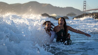 couple embracing while being crushed by a large wave at the beach