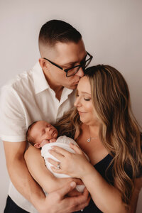 Newborn Photographer in Charleston - Parents embrace their infant during Newborn Portrait Session in Charleston, SC.