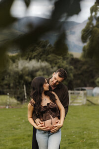 Expecting couple embracing during an outdoor maternity session in Christchurch