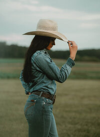 Senior portrait at Triple T Farms in Fruitdale, Alabama — side view, tipping her cowboy hat and
looking down.