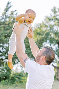 Dad tosses toddler in the air during a Dallas photo session with plano family photographer ling waters photography