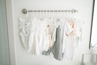 Cute baby clothes hanging on hangers in Raleigh baby photography studio