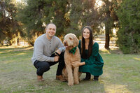 Couple crouching beside their dog smiling during an outdoor lifestyle portrait session photographed by Kaitlyn Dawn Photography.