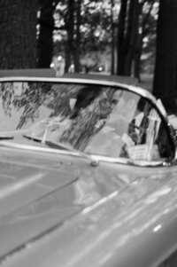 Bride and groom kiss as they drive in their convertible
