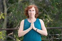 Woman in a simple yoga pose with hands together in front of chest.