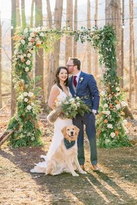 Wedding couple with their dog under a winter greenery arbor by Flowergirl Cville at Indigo House, near Charlottesville, VA | Photo by Xiaoqi Li Photography