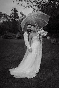 Couple de mariés sous un parapluie transparent lors d’un mariage pluvieux et moody dans les Laurentides, photographié par Jeff Gagnon photographe.