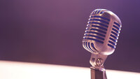 Silver microphone in front of a pink background