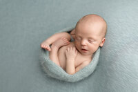 Baby boy wrapped in a soft robins egg blue wrap during his newborn portrait session with Jennifer Brandes Photography.