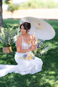 bride sitting with parasol under tree at rainbow oaks ranch in sanger california