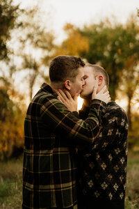 Same-sex couple kissing in autumn outdoor engagement or wedding portrait session.