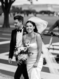 Black and white photo of a couple crossing the sidewalk in Washington DC on their wedding day.