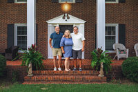 Three adult siblings standing on brick steps in front of a historic home during a family session in New Bern