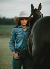 Senior portrait at Triple T Farms in Fruitdale, Alabama — view from behind the horse as she
stands beside it, facing the camera.