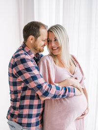 Husband hugging his wife from behind while she looks over at him