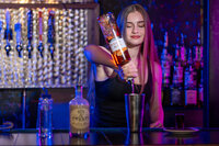 A bartender pouring alcohol into a mixer