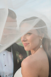 Bride looks through her veil blowing in the wind