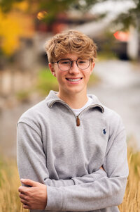 A boy from Brookfield Central High School stands in downtown Waukesha in a gray quarter-zip for his senior photos.