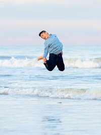 Tween boy leaping high above the waves during a beach family portrait session. (Photographed by Nature's Child Photography)