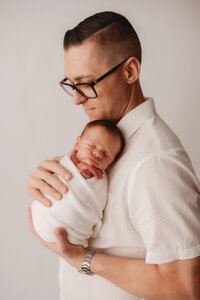 Newborn Photographer in Charleston -Father embraces his infant during Newborn Portrait Session in Charleston, SC.