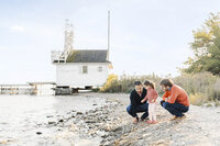 2 dads and their daughter looking at rocks to throw into the water at Cherry Beach, toronto