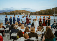 Bride and groom at their wedding ceremony at The Ridges Resort on Lake Chatuge, in front of a floral arch by the water.