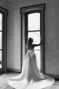 A bride in her wedding dress at the Surf Hotel, looking out the window.